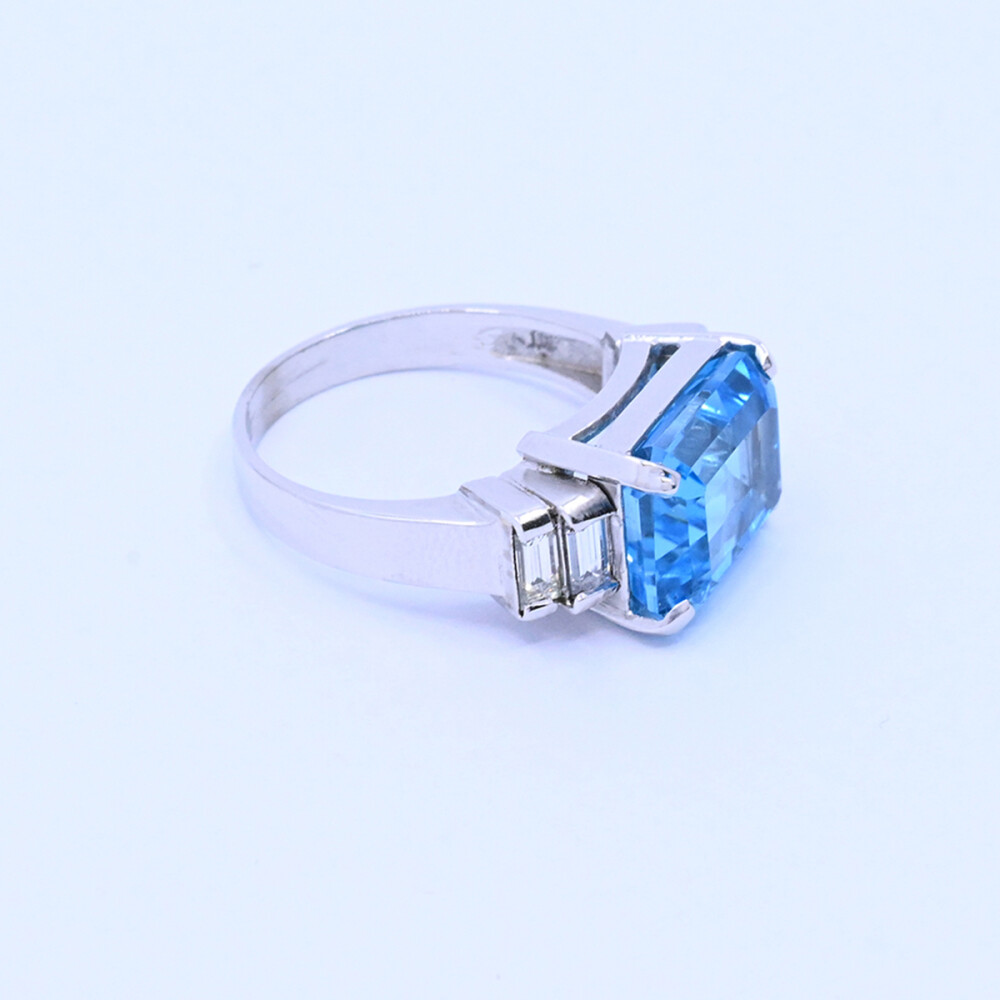 Anillo oro 18k blanco con topacio azul central y 4 brillantes baguette. Anillo oro 18k blanco con topacio azul central y 4 brillantes baguette.