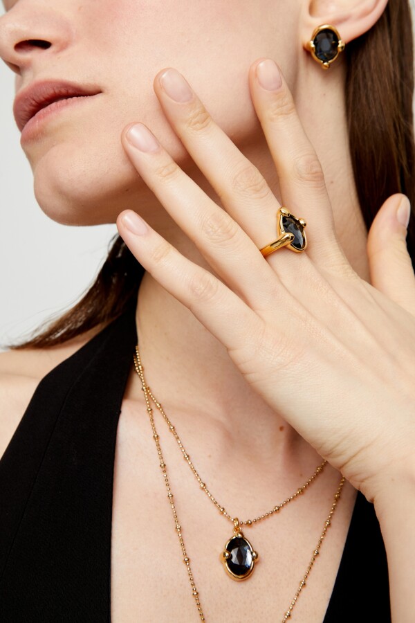 ANILLO DE ALEACIÓN DE METALES BAÑADO EN ORO 18K CON UN CRISTAL FACETADO GRIS Anillo