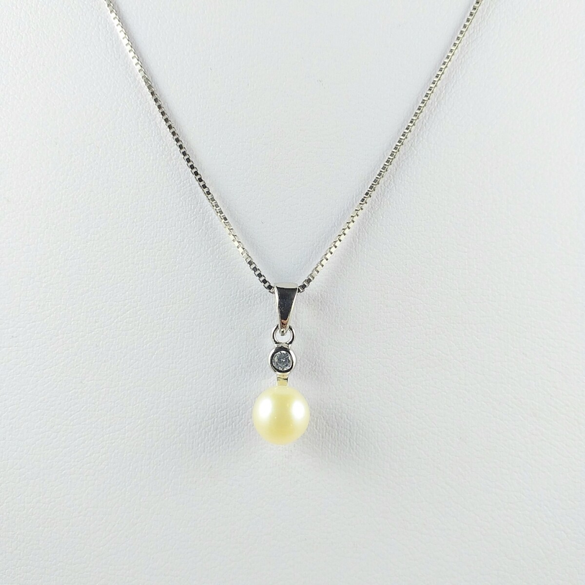 Colgante con perla natural de rió 6 1/2 mm y circonia de 3 mm, con cadena veneciana de plata y baño de oro gris. 
