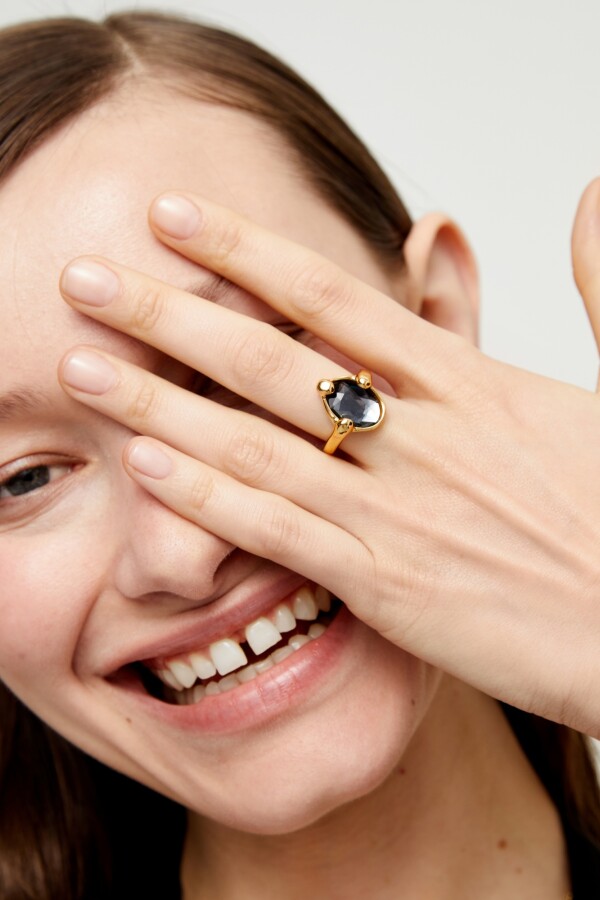 ANILLO DE ALEACIÓN DE METALES BAÑADO EN ORO 18K CON UN CRISTAL FACETADO GRIS Anillo