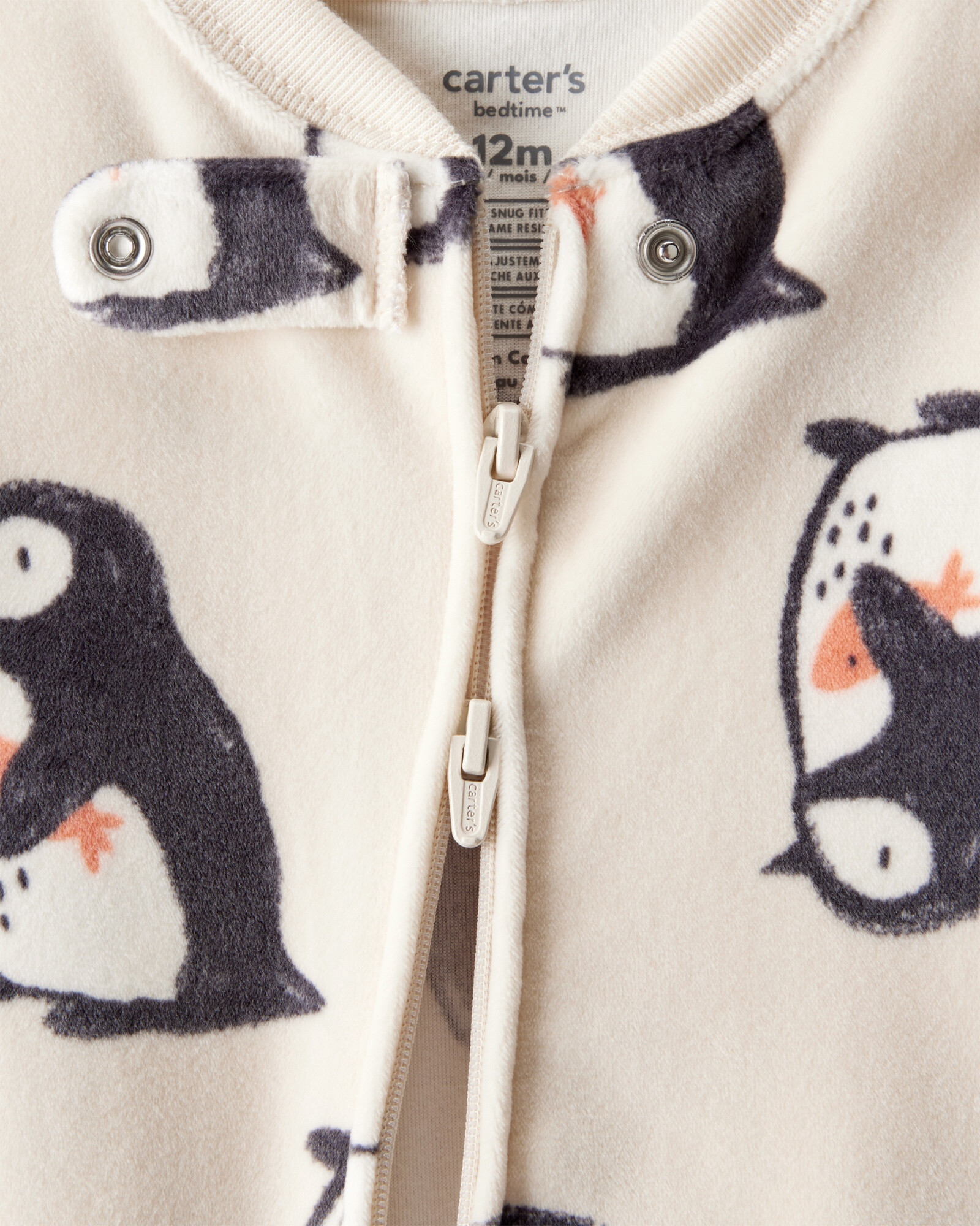 Pijama una pieza de DreamPlush, con pie, crema, diseño pingüinos. Talles 12-24M Sin color
