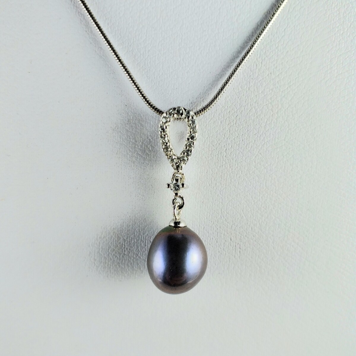 Colgante con perla natural de río negra 10 mm*8.5 mm y circonias con cadena de plata 925 con baño de oro gris . 