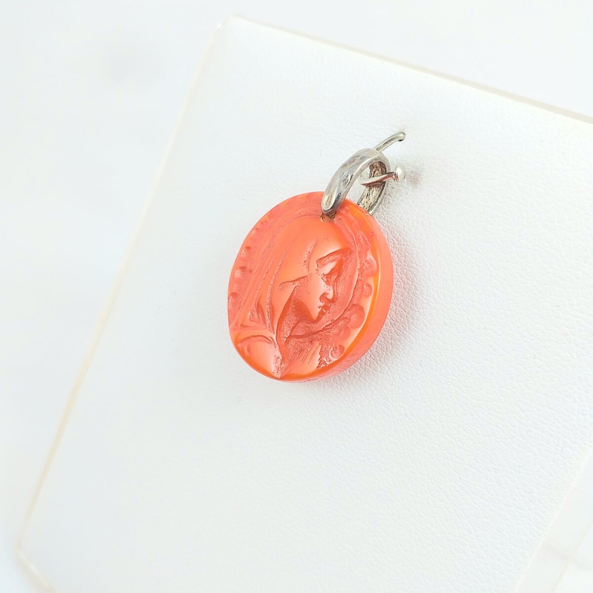 Medalla religiosa en resina de Virgen niña con manto color naranja, medidas 2.2cm, argolla de plata 925. 
