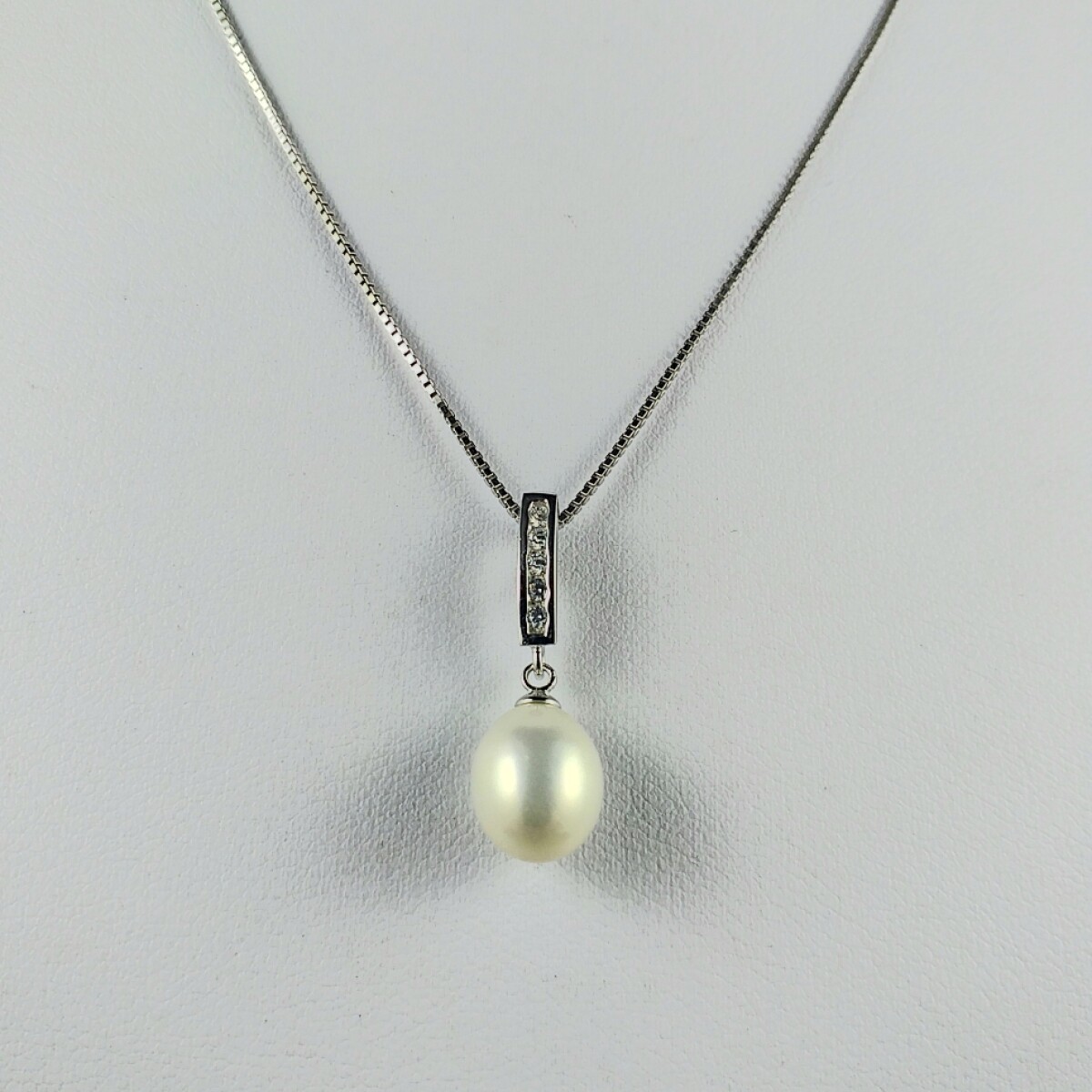 Colgante de plata 925 y baño de oro gris con perla natural de río de 10 mm * 8 mm y barrita con 5 circonias. 