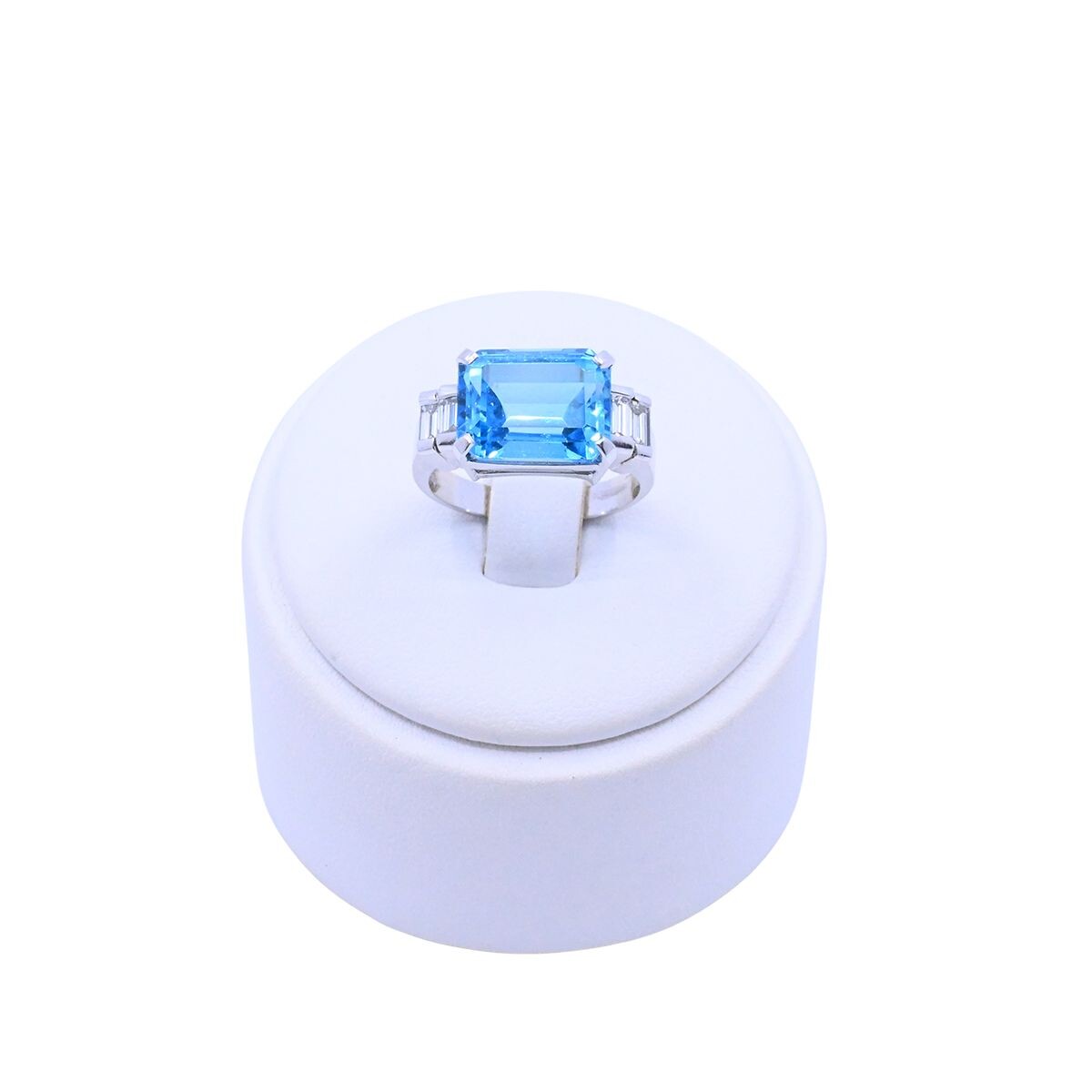 Anillo oro 18k blanco con topacio azul central y 4 brillantes baguette. 