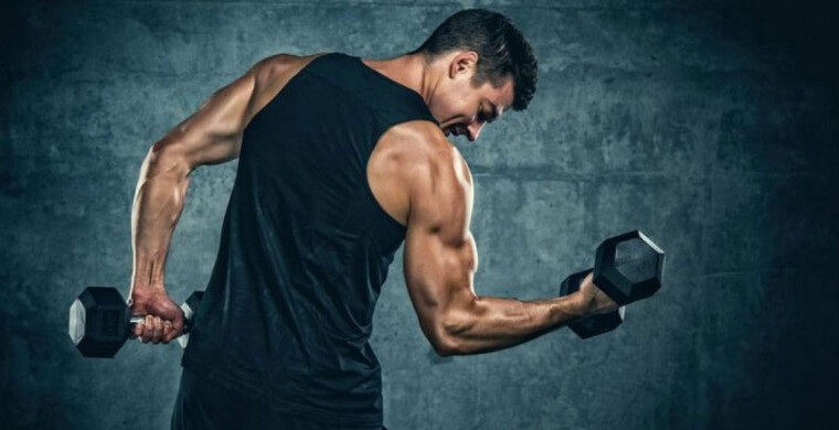 Entrenando en el gimnasio. Hombre con grandes músculos levantando peso  mientras entrena en el gimnasio. Ponerse en forma. Stock Photo